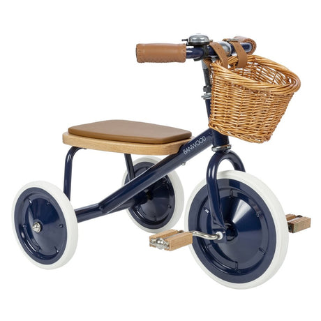 Rowerek trójkołowy Banwood Trike Navy Blue z wiklinowym koszykiem, dębowym siedziskiem i drewnianymi pedałami dla dzieci.