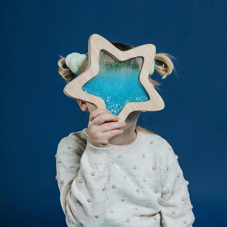 Drewniana zabawka edukacyjna Petit Boum, świecąca w ciemności sensoryczna gwiazda z brokatem i fluorescencyjnym piaskiem.