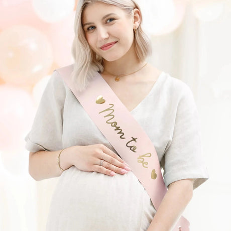 Różowa szarfa Baby Shower z złotym napisem "Mom to Be" Partydeco, idealna dla przyszłej mamy, wyjątkowy dodatek i pamiątka.